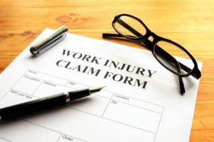 work injury claim form with glasses and a pen on paper