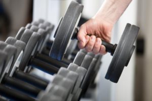 a man’s hand picking up a dumbbell