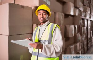 Warehouse employee wearing safety helmet viewing safety tips on clipboard